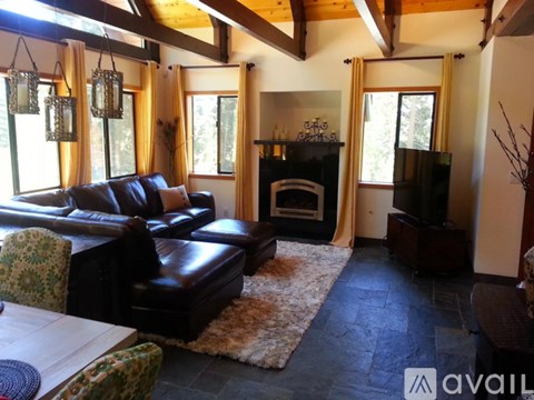 A living room with a black leather couch and a fireplace.