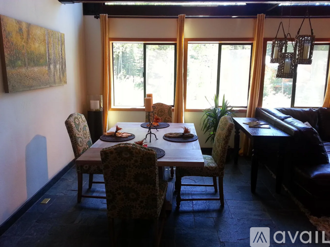 A dining room with a table set for two and a couch.