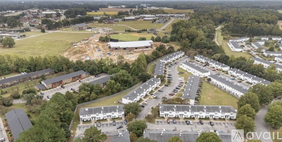 An aerial view of a parking lot and buildings with trees in the background.