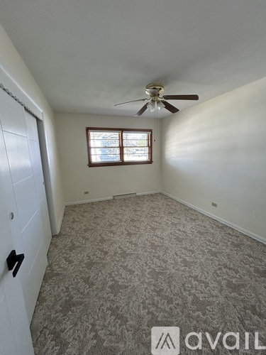 A room with a ceiling fan and a window with a view of a building outside.