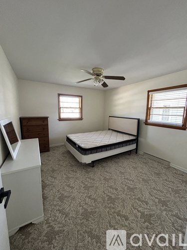 A bedroom with a bed, dresser, and window.