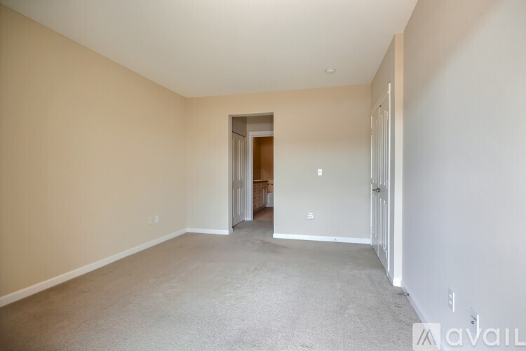 A spacious room with a carpeted floor and a doorway leading to another room.