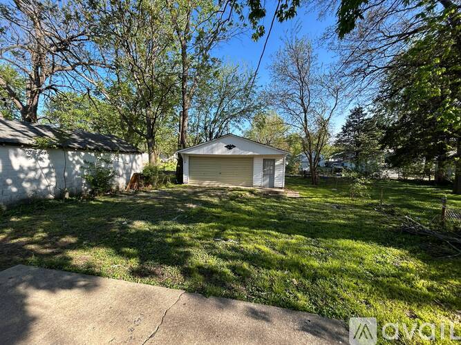 A house with a white garage door is surrounded by trees.