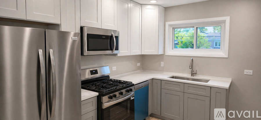 A modern kitchen with a stainless steel refrigerator and a window.