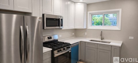 A modern kitchen with a stainless steel refrigerator and a window.