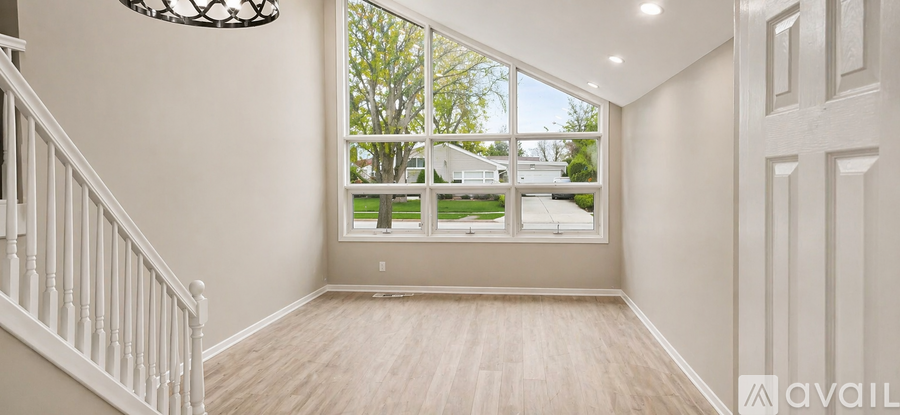A spacious room with wooden floors and a staircase leading to the upper level.