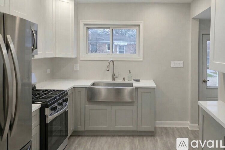 A kitchen with a stainless steel refrigerator and a window.