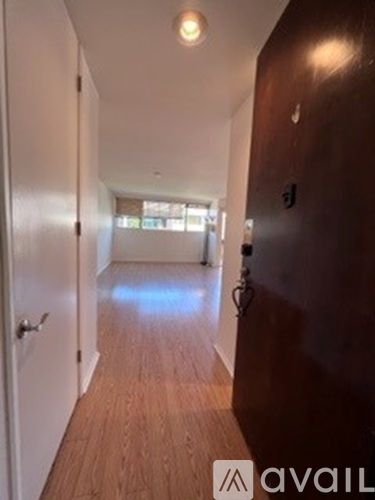 A hallway with a wooden floor and white walls.