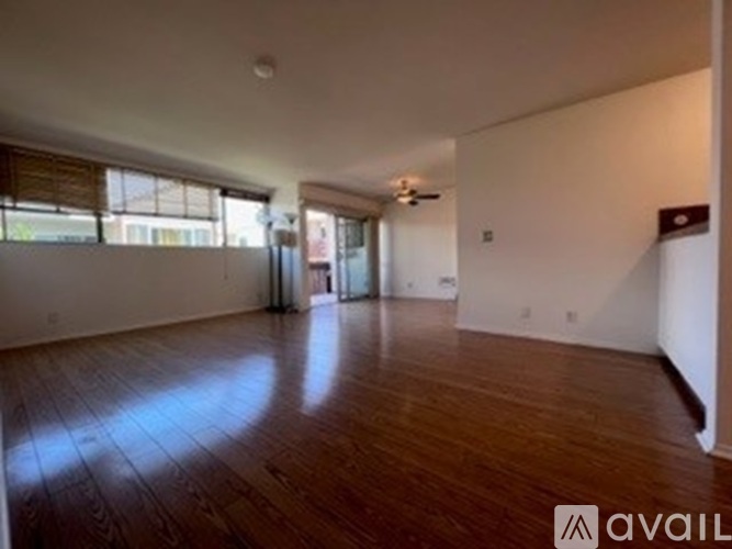 A spacious room with wooden floors and a ceiling fan.