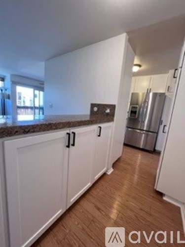 A kitchen with white cabinets and a wooden floor.