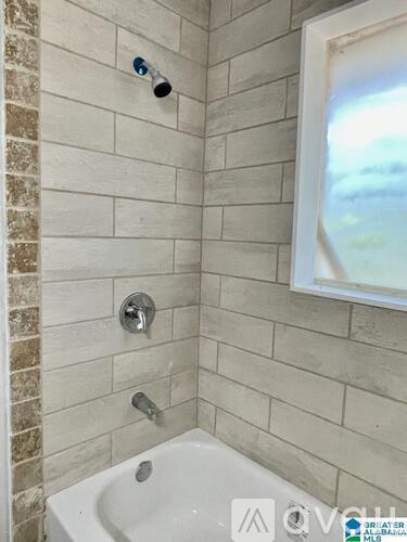 A white bathtub in a bathroom with a shower head and faucet.
