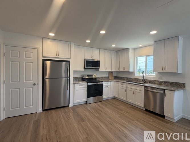 A kitchen with white cabinets and a wooden floor.