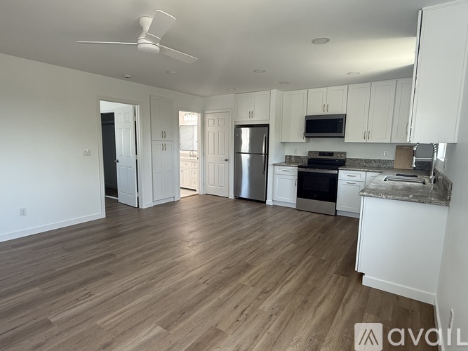 A kitchen with white cabinets and a wooden floor.