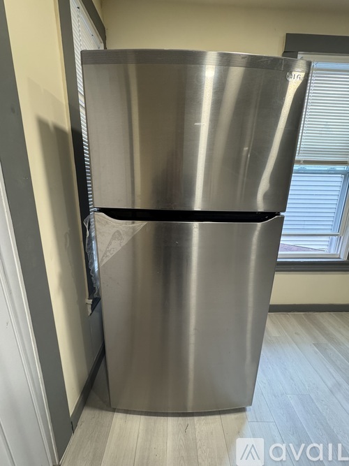 A stainless steel refrigerator with a black handle is in a room.