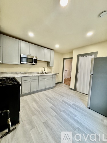 A kitchen with white cabinets and a black trash can.