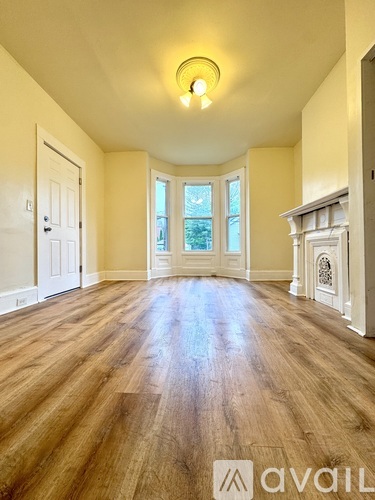 A spacious room with wooden floors and a fireplace.
