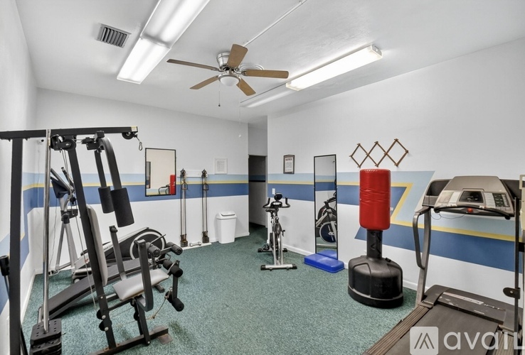A gym with a variety of equipment including a treadmill, weights, and a fan.