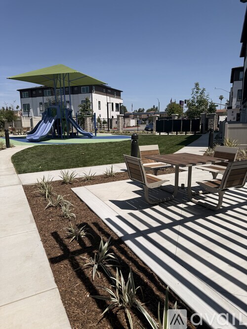 A playground with a slide and a green umbrella.