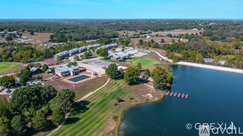 An aerial view of a lake with a building and trees in the foreground.
