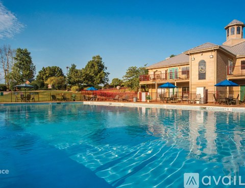 A large swimming pool in front of a building with a clock on the wall.