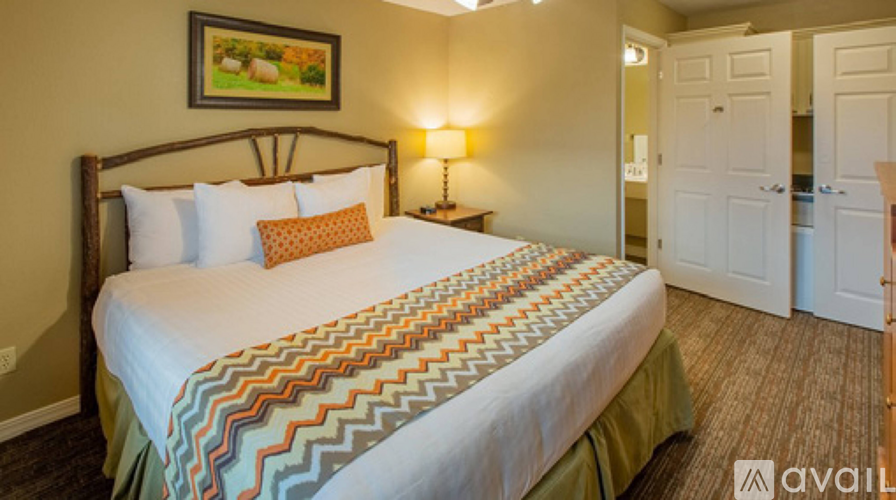 A bedroom with a large bed and a painting on the wall.