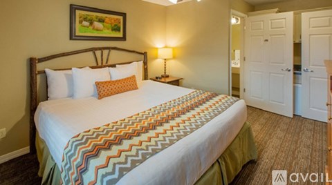 A bedroom with a large bed and a painting on the wall.