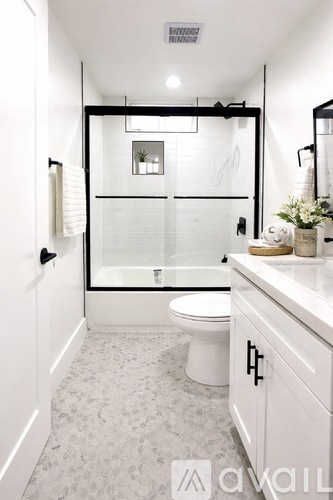 A white bathroom with a glass shower door and a toilet.