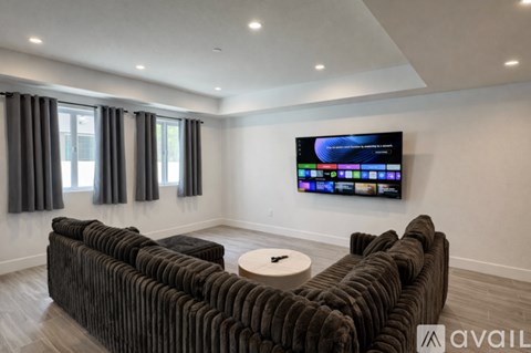 A living room with a large television and a brown couch.