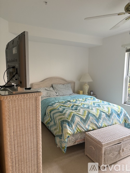 A bedroom with a bed, a television, and a ceiling fan.