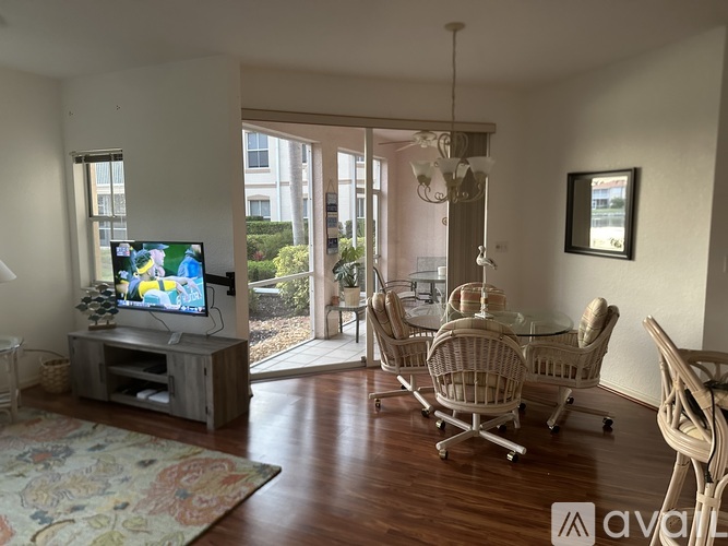 A living room with a television, chairs, and a glass table.