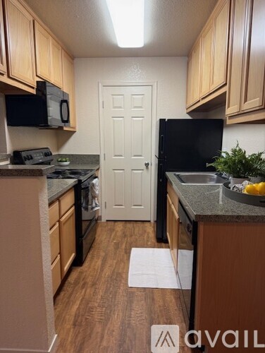 A kitchen with wooden cabinets and a black fridge.
