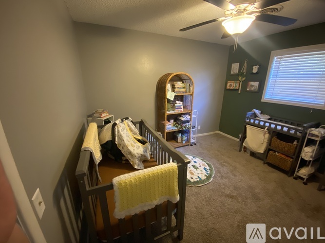 A baby's room with a crib, a rocking chair, and a bookcase.