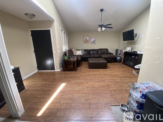 A living room with a brown couch and a ceiling fan.