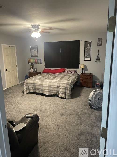 A bedroom with a bed, chair, and ceiling fan.
