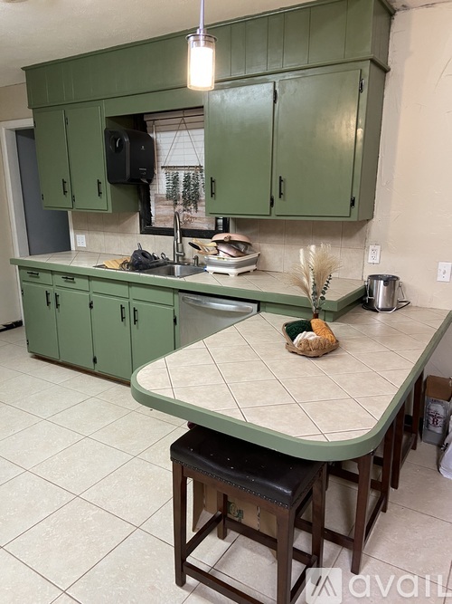 A kitchen with green cabinets and a white island.