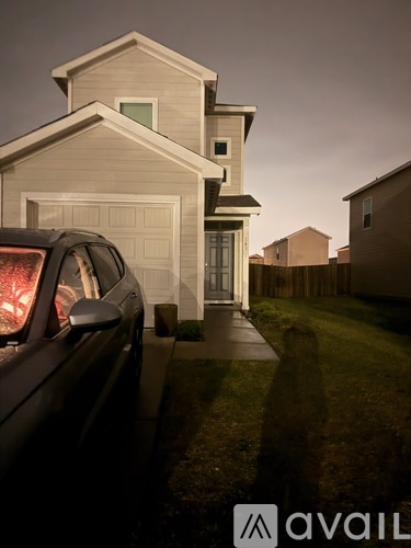 A car is parked in front of a house with a garage.