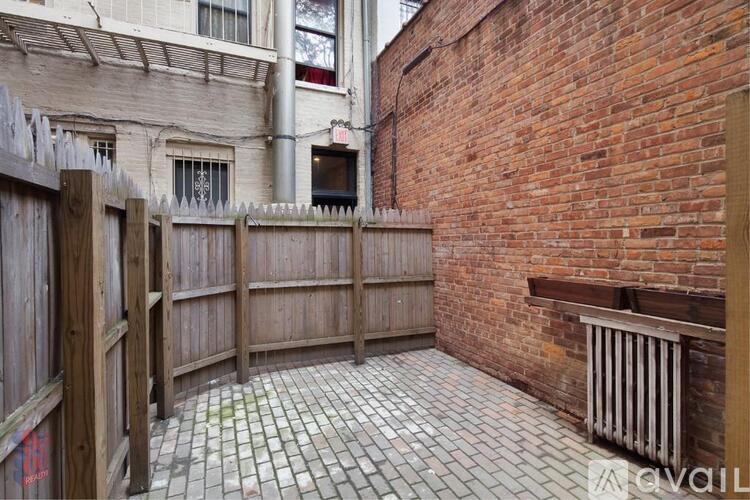 A patio with a brick wall and a wooden fence.