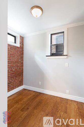 A room with a wooden floor and a window with blinds.