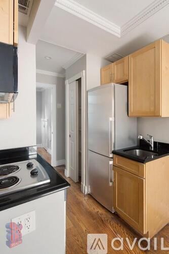 A kitchen with wooden cabinets and a stainless steel refrigerator.