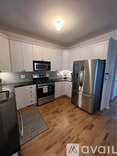 A kitchen with wooden floors and white cabinets.