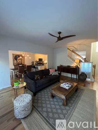 A living room with a black couch, a coffee table, and a ceiling fan.