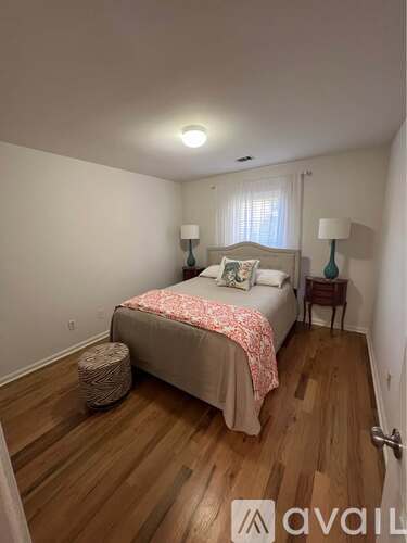 A bedroom with a bed, two lamps, and a basket on the floor.