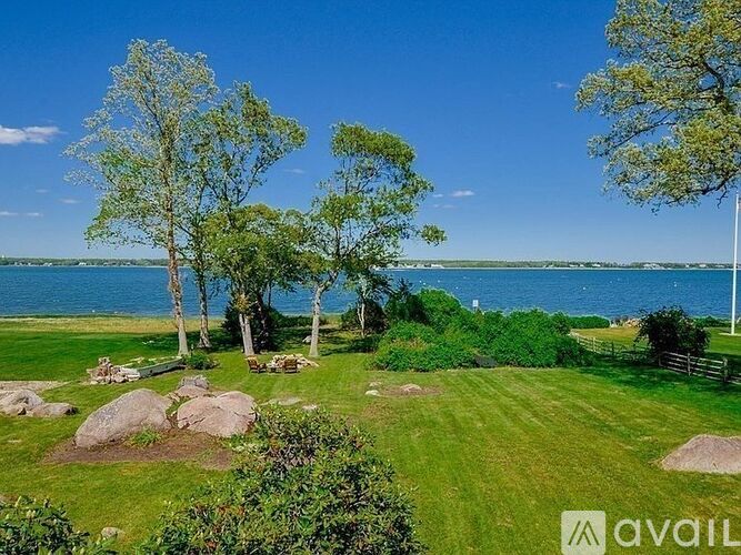A grassy area with trees and a body of water in the distance.