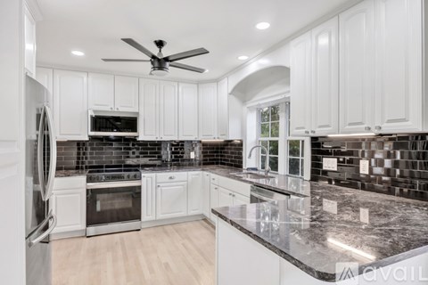 A kitchen with white cabinets and a black countertop.