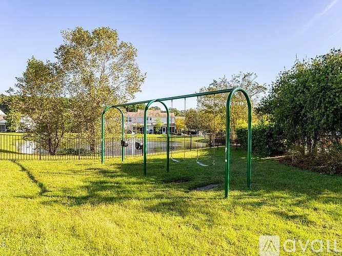 A playground with a green swing set in a grassy area.