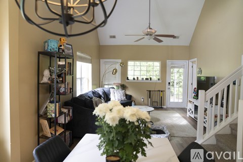 A living room with a couch, a table with a vase of flowers, and a bookshelf.