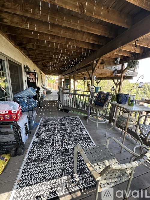 A covered patio with a black and white rug and metal chairs.