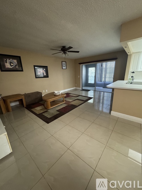 A living room with a ceiling fan and a rug on the floor.