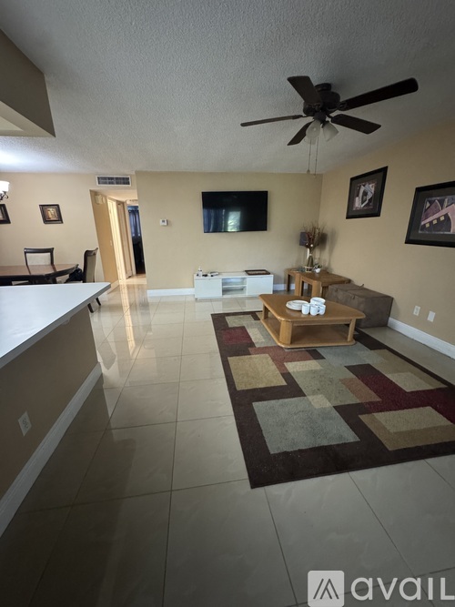 A living room with a rug on the floor and a ceiling fan above.