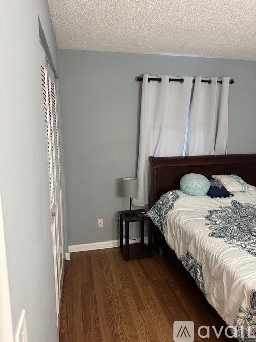A bedroom with a bed, nightstand, and lamp.